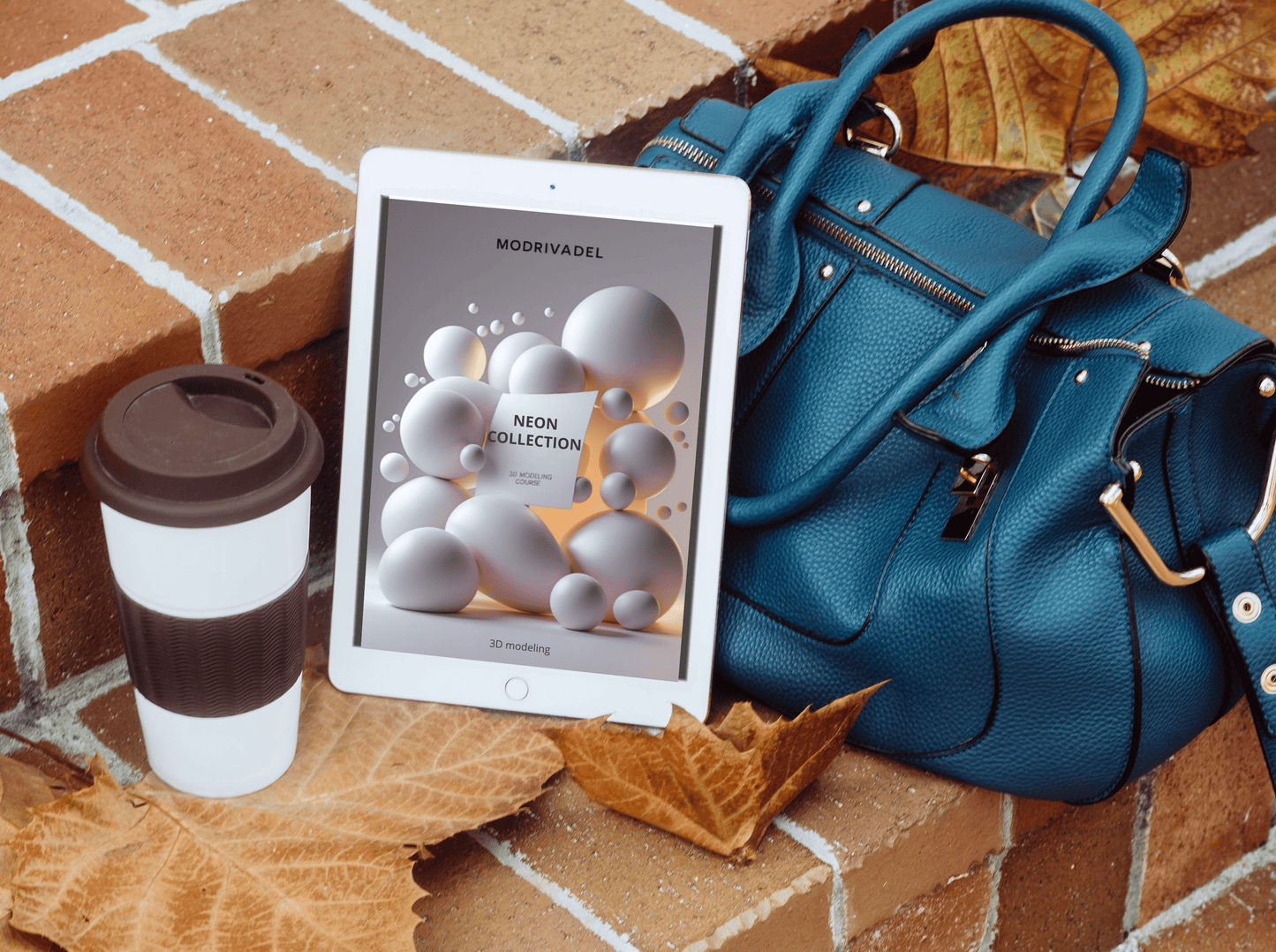 Blue handbag, white and brown coffee cup, and tablet with a product display on a brick surface.