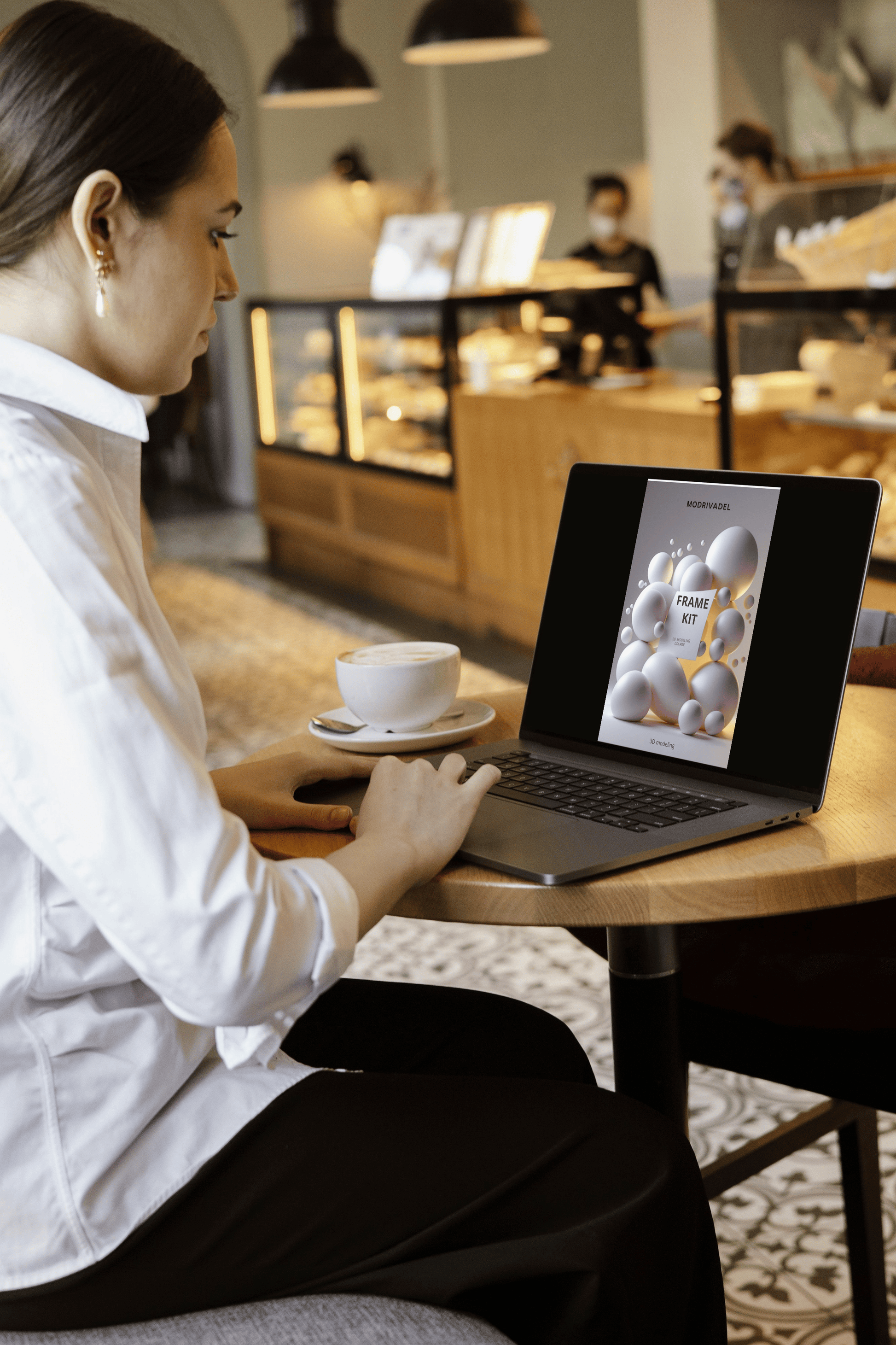 Woman using a laptop in a cafe with a cup of coffee on the table