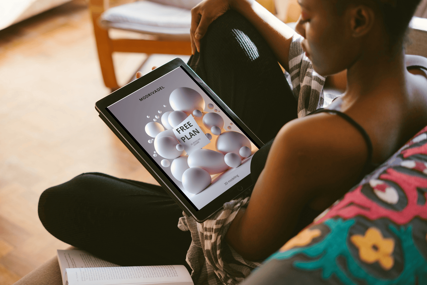 Person holding a tablet with a free plan offer on the screen, sitting on a couch.